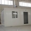 A prefabricated enclosure in an industrial facility. A worker can be seen using a saw to trim construction materials.