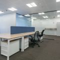 A large, modern office space with desks and chairs, with partitions separating different areas and creating different spaces.
