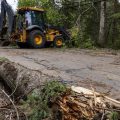 Power lines and trees have sustained damage. There are emergency services present at the scene and a bulldozer.
