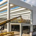 There is the skeleton frame of a warehouse under construction. A large yellow crane extends into the building.