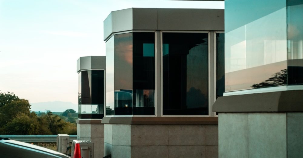 Multiple tollbooths with polarized glass create a checkpoint for a vehicle passing through on a highway.