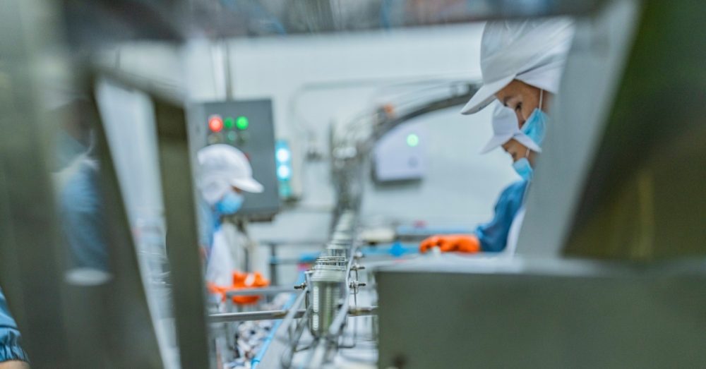 A bagging area in a food processing plant where workers practice hygienic protocols by wearing gloves and masks.