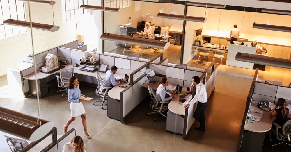 A bird's-eye view of an open concept office space with various people sitting at desks and working on computers.