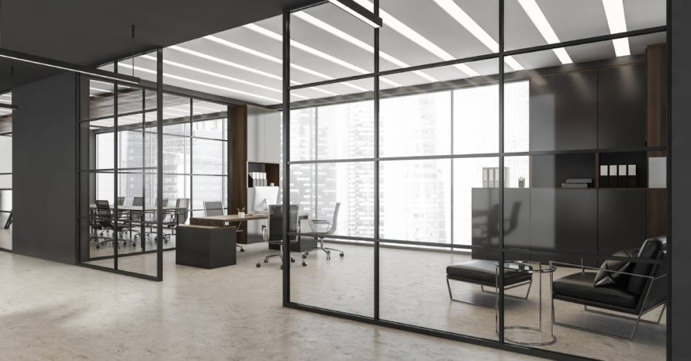 An office space with transparent walls made from glass provides a look into two large rooms. The walls are gray and modern.