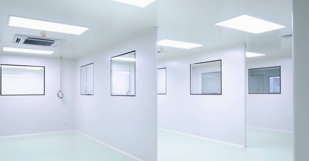 A bright white room with powerful lighting is divided into three sections with walls. Each wall has two windows.