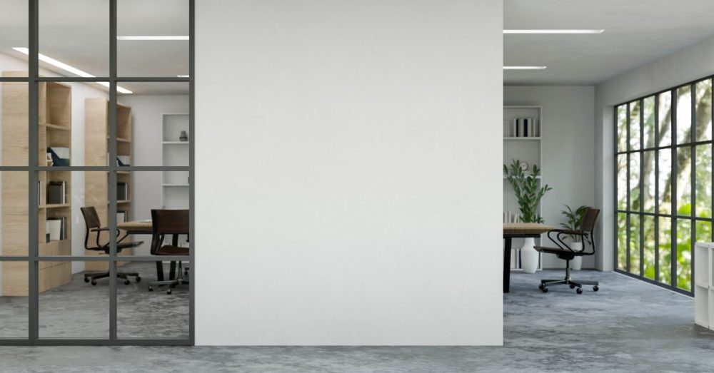 A focus on a blank building wall in an office, separating a larger space from another office room.
